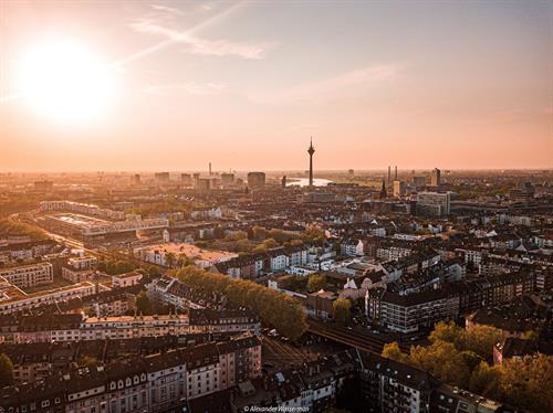 Luftaufnahme von Düsseldorf im Abendlicht, im Vordergrund der Stadtteil Bilk, weiter hinten der Fernsehturm und der Rhein.